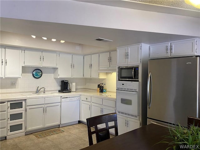 kitchen with stainless steel appliances, a sink, visible vents, and white cabinets