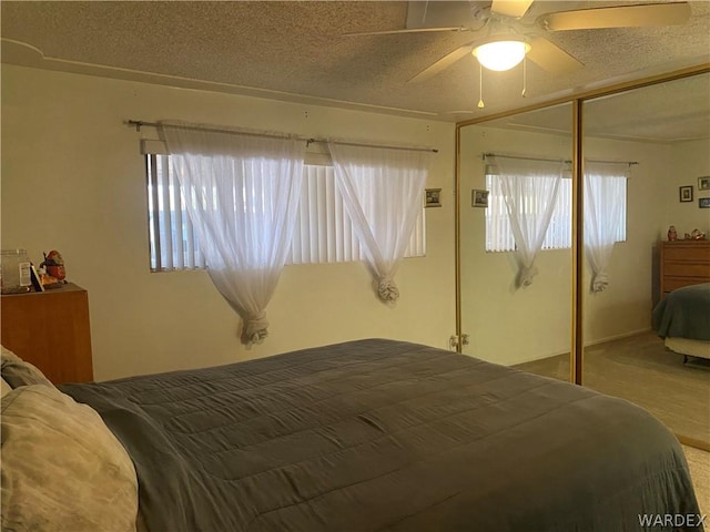 carpeted bedroom featuring multiple windows, ceiling fan, and a textured ceiling