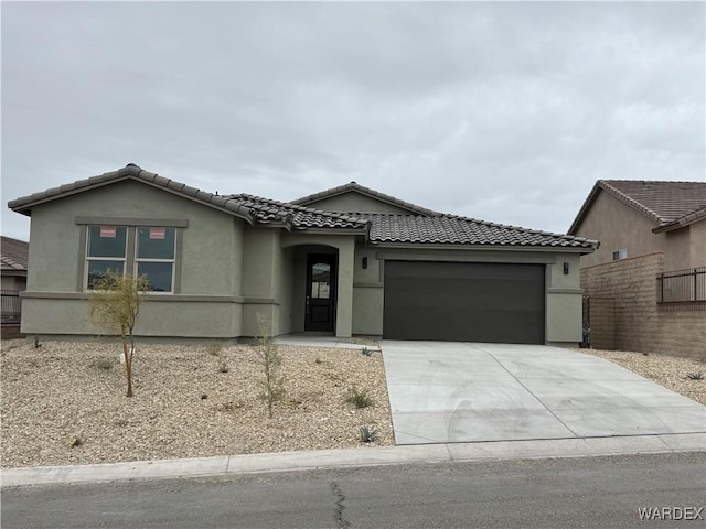 view of front of property with a garage, concrete driveway, a tile roof, and stucco siding