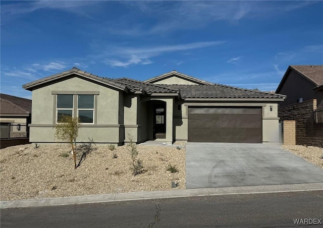 ranch-style house with a garage, concrete driveway, a tile roof, and stucco siding