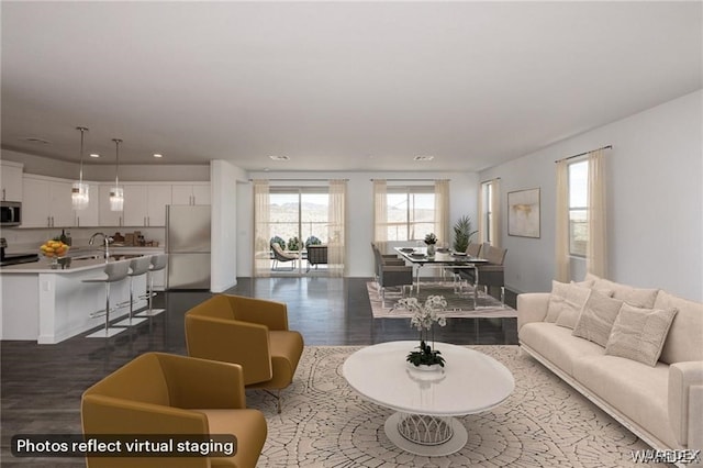 living area with dark wood-type flooring and recessed lighting