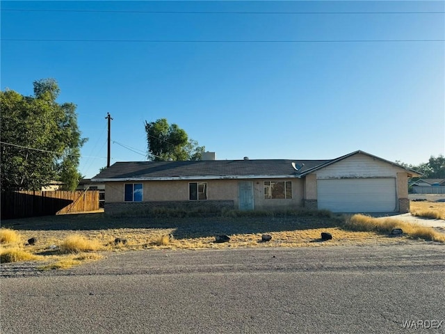 ranch-style house with a garage, fence, and stucco siding