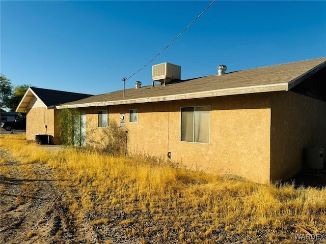 back of house with central air condition unit and stucco siding