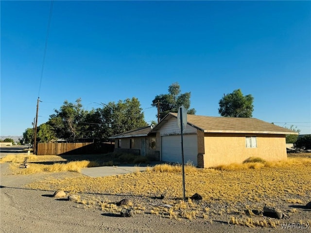 view of front of property featuring a garage, fence, and stucco siding