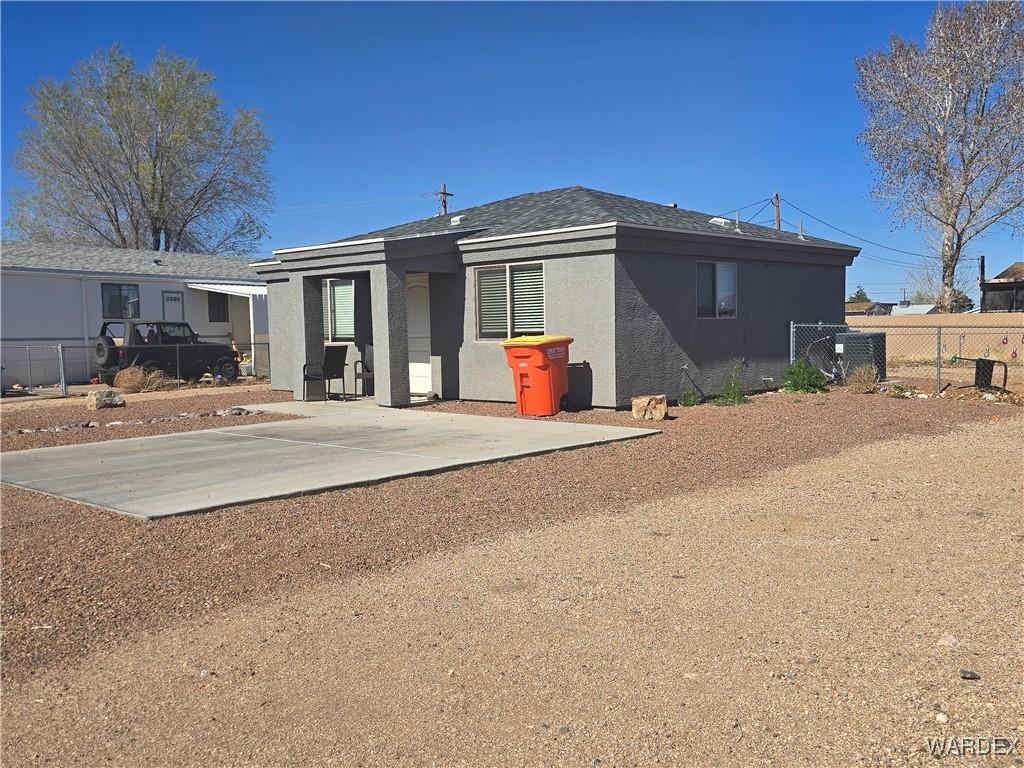 back of property with a patio, fence, dirt driveway, and stucco siding