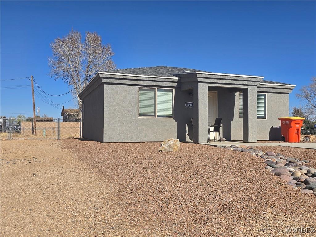 view of front facade featuring stucco siding and fence