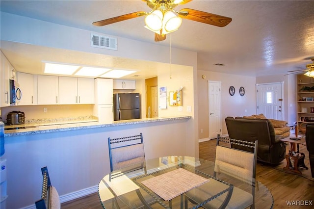 dining area featuring dark wood-style flooring, visible vents, and baseboards