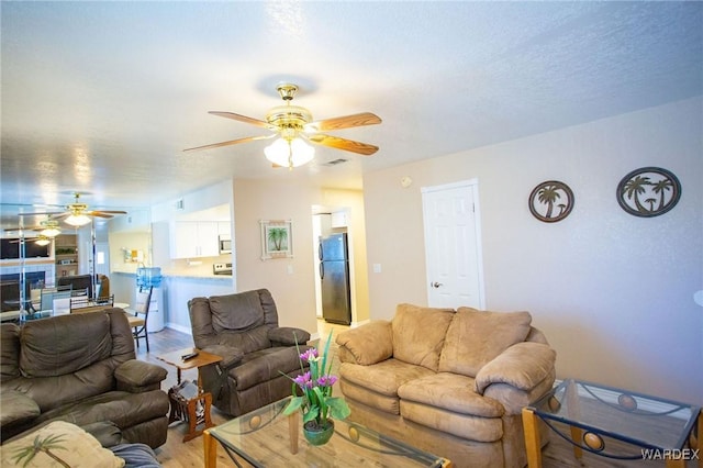 living area with visible vents, light wood finished floors, and a ceiling fan