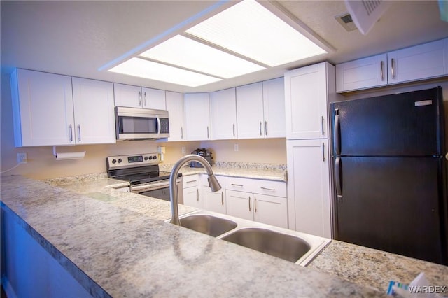 kitchen featuring stainless steel appliances, white cabinetry, and a sink