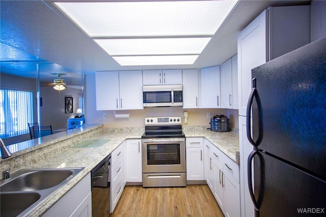 kitchen featuring white cabinets, a sink, a peninsula, and black appliances