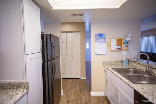 kitchen with black appliances, visible vents, white cabinetry, and a sink