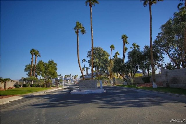 view of street featuring curbs, a gated entry, and a residential view