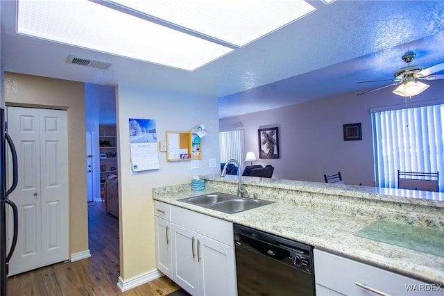 kitchen with visible vents, white cabinetry, a sink, light wood-type flooring, and dishwasher