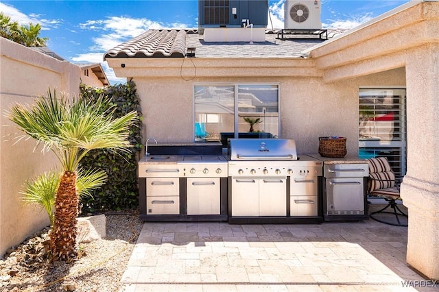 view of patio with a sink, a grill, area for grilling, central AC, and fence