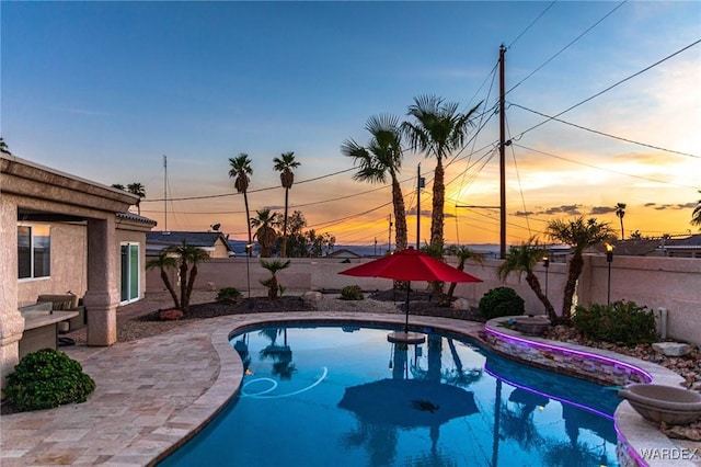 pool at dusk featuring a fenced backyard, a fenced in pool, and a patio