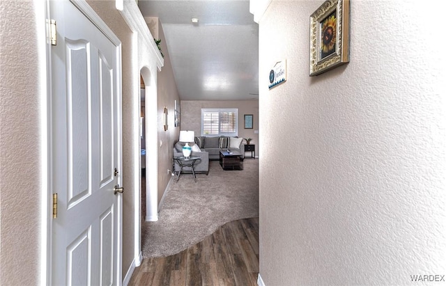hall with a textured wall and dark wood-style floors