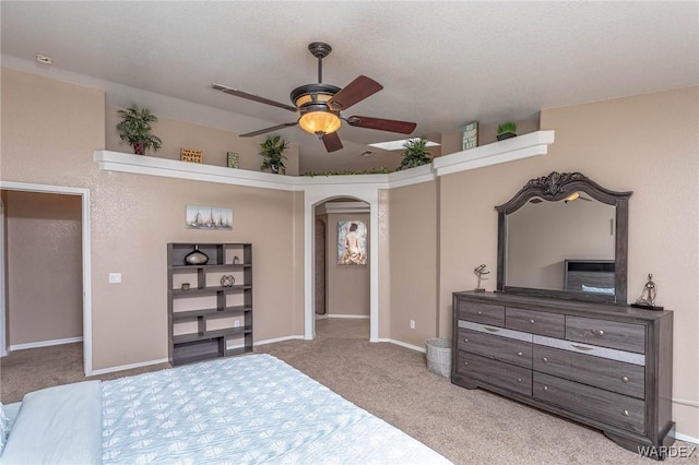 carpeted bedroom with baseboards, arched walkways, and ceiling fan