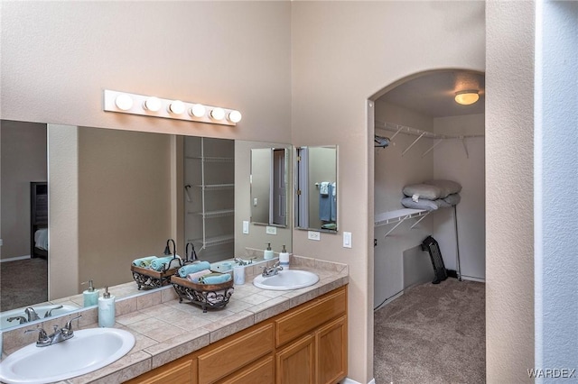 full bathroom featuring a walk in closet, double vanity, and a sink