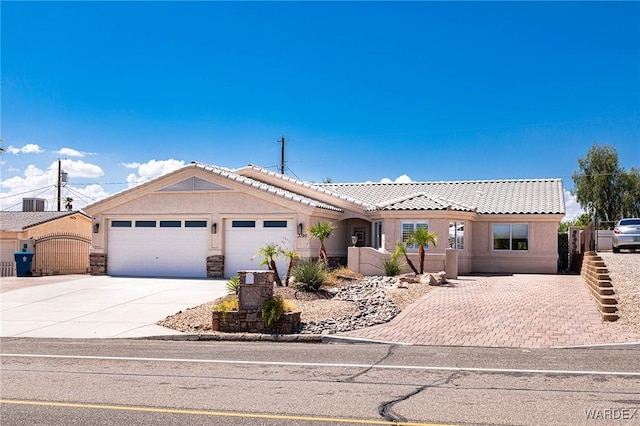 ranch-style house with a tiled roof, a gate, driveway, and stucco siding
