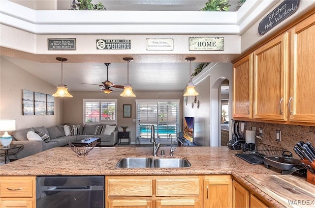 kitchen featuring open floor plan, a ceiling fan, backsplash, arched walkways, and a sink