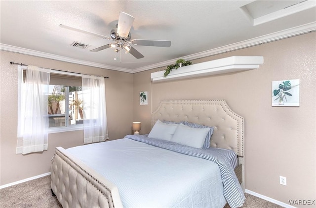 carpeted bedroom featuring crown molding, a ceiling fan, visible vents, attic access, and baseboards