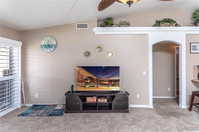 carpeted living area with visible vents, baseboards, arched walkways, ceiling fan, and lofted ceiling