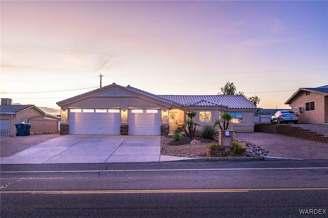 ranch-style home featuring a garage, stucco siding, stone siding, a gate, and concrete driveway