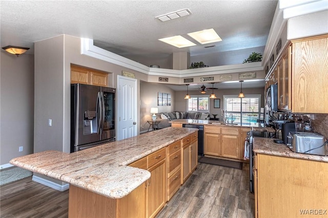 kitchen featuring visible vents, appliances with stainless steel finishes, a peninsula, dark wood finished floors, and light stone countertops