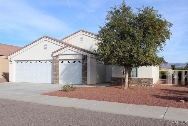 single story home with a garage, fence, stone siding, driveway, and stucco siding