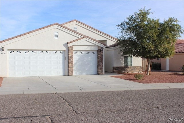 ranch-style home featuring an attached garage, a tile roof, stone siding, concrete driveway, and stucco siding