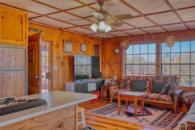 living room with wood walls, ceiling fan, coffered ceiling, and wood finished floors