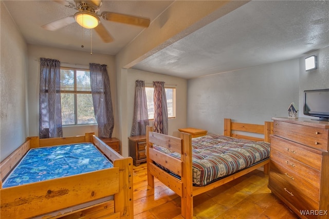 bedroom with ceiling fan, a textured ceiling, and hardwood / wood-style flooring