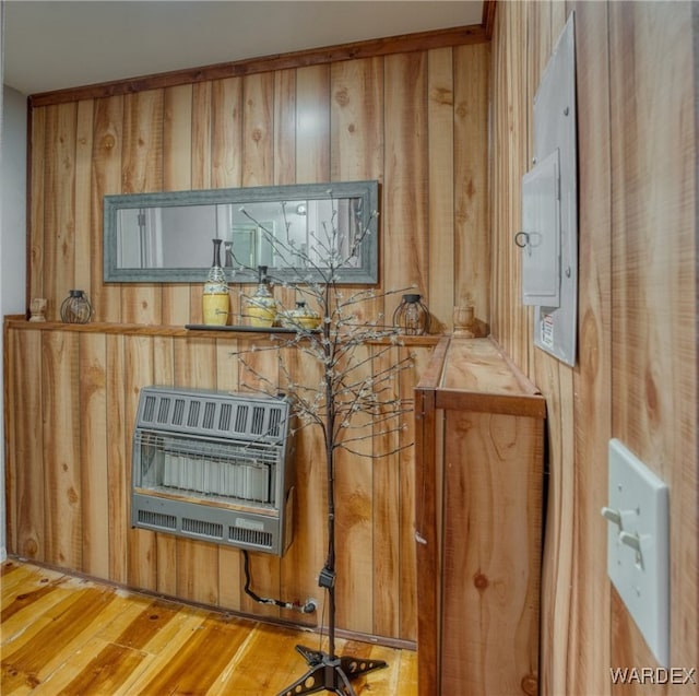 interior details with heating unit, wood walls, and wood finished floors