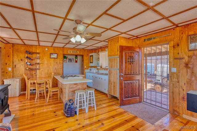 kitchen with a wood stove, light wood finished floors, coffered ceiling, and wood walls