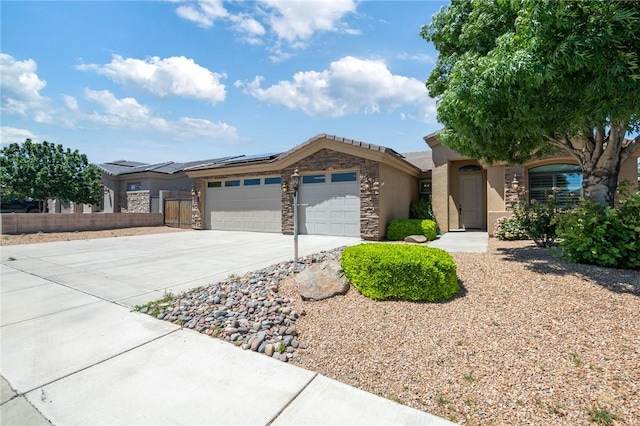 1999 Alan Ladd Dr, Kingman, AZ 86409 - view of front of home with an attached garage, solar panels, driveway, stone siding, and fence