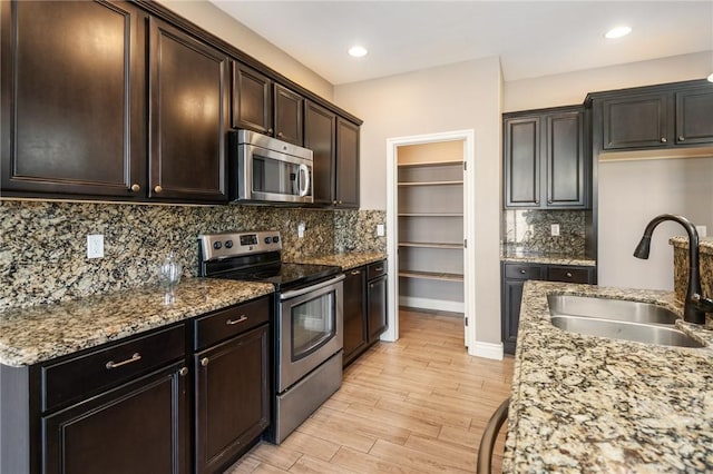 1999 Alan Ladd Dr, Kingman, AZ 86409 - kitchen with stainless steel appliances, a sink, light wood finished floors, light stone counters, and tasteful backsplash