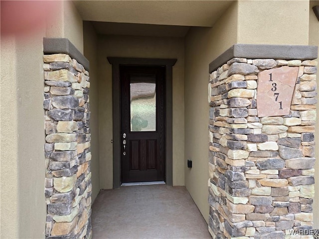 property entrance featuring stone siding and stucco siding