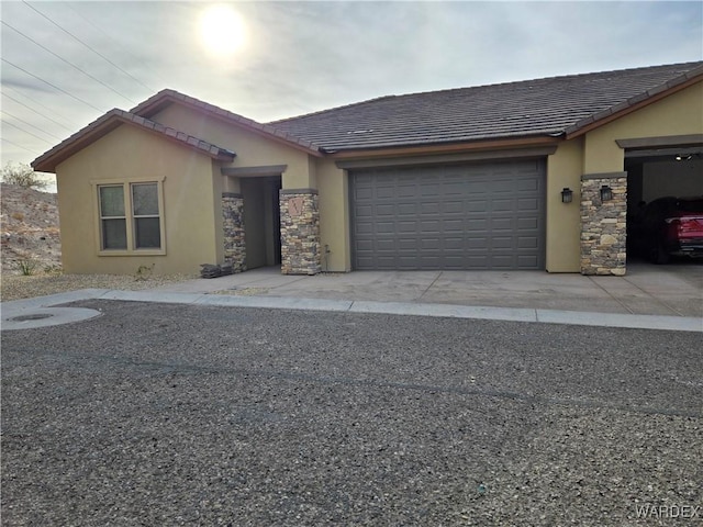 view of front of home with a garage, stone siding, a tile roof, and stucco siding