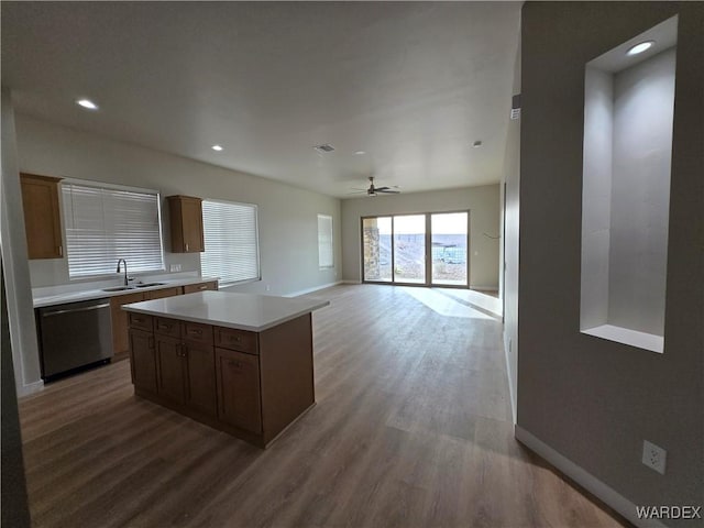 kitchen featuring light countertops, stainless steel dishwasher, open floor plan, a kitchen island, and a sink