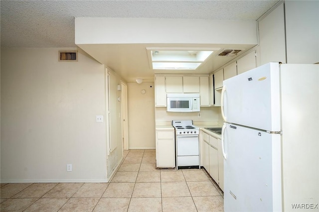 kitchen featuring white appliances, light tile patterned floors, visible vents, light countertops, and a textured ceiling