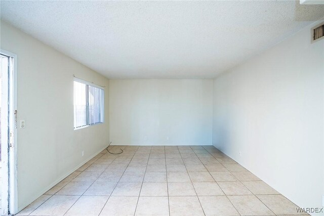 spare room with visible vents, a textured ceiling, and light tile patterned floors