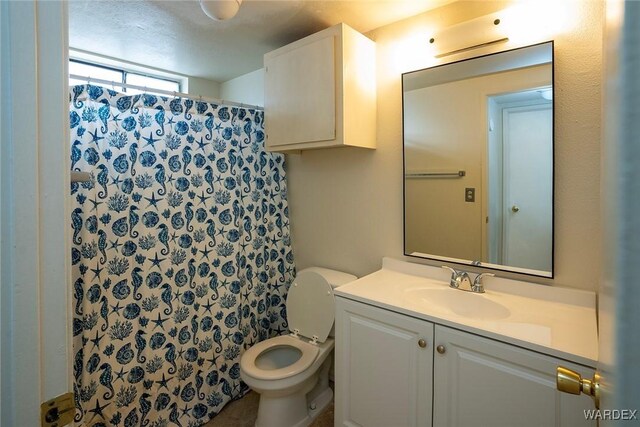 bathroom with curtained shower, vanity, and toilet