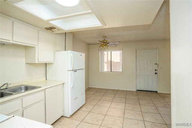 kitchen with a sink, visible vents, white cabinets, light countertops, and freestanding refrigerator