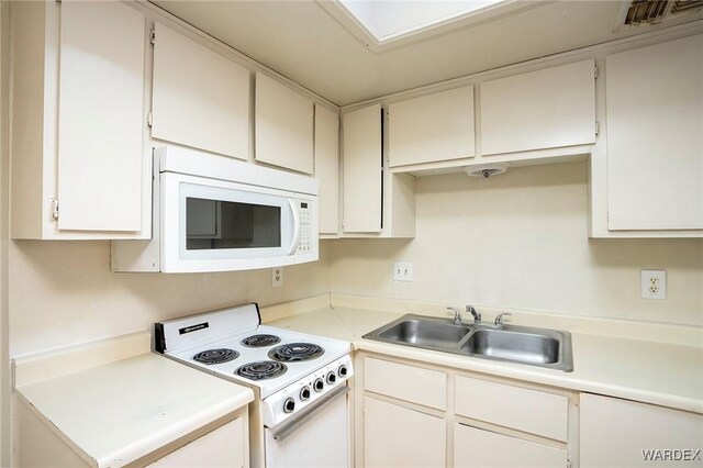 kitchen with white appliances, a sink, visible vents, white cabinetry, and light countertops