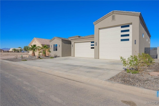 view of front facade with a garage, concrete driveway, and stucco siding