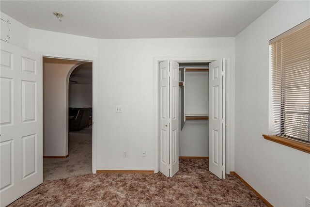 6045 S Klamath Loop, Fort Mohave, AZ 86426 - unfurnished bedroom with carpet, arched walkways, a closet, and baseboards
