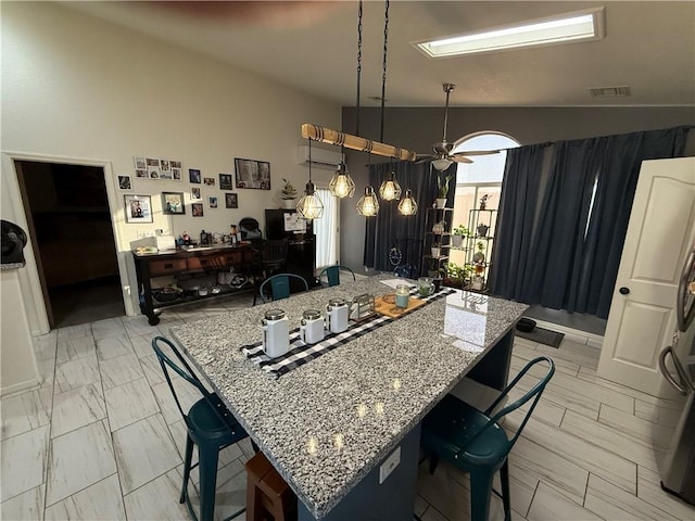 3483 Via Los Pozos, Bullhead City, AZ 86442 - kitchen featuring lofted ceiling, a desk, a kitchen bar, a wall mounted air conditioner, and light stone counters