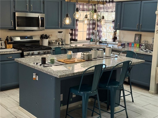 3483 Via Los Pozos, Bullhead City, AZ 86442 - kitchen featuring stainless steel appliances, a center island, a breakfast bar, light stone countertops, and blue cabinetry