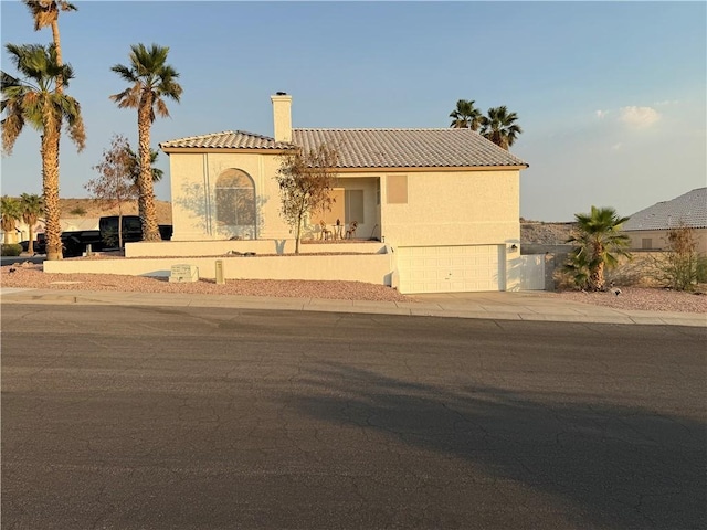 3483 Via Los Pozos, Bullhead City, AZ 86442 - mediterranean / spanish-style house featuring a tile roof, a chimney, a garage, stucco siding, and concrete driveway