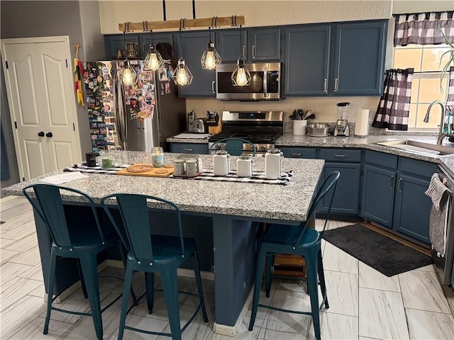 3483 Via Los Pozos, Bullhead City, AZ 86442 - kitchen with appliances with stainless steel finishes, blue cabinetry, a breakfast bar, a kitchen island, and light stone counters